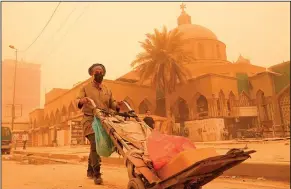  ?? ?? A man pushes a cart during a sandstorm.