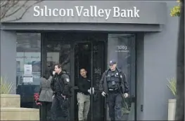  ?? Jeff Chiu Associated Press ?? POLICE OFFICERS exit Silicon Valley Bank in Santa Clara on Friday. The FDIC says insured depositors will have access to their deposits no later than Monday.