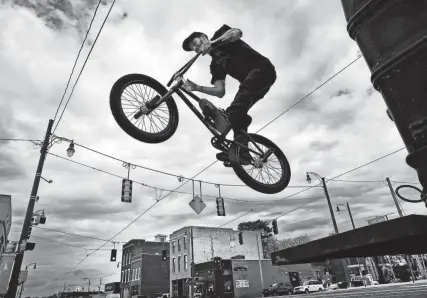  ?? THE COMMERCIAL APPEAL FILES ?? April 20, 2016: Floating above the Pinch District, BMX freestyle biker Dillon Leeper with FBM Bike Company from Richmond, Virginia, pulls tricks off the back of the company’s tour bus during a stop north of downtown.