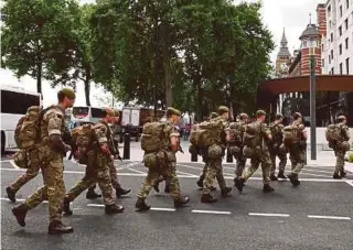  ??  ?? British soldiers arriving by bus and heading toward a building next to New Scotland Yard police headquarte­rs near to the Houses of Parliament in central London yesterday.