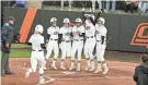  ?? DEVIN LAWRENCE WILBER/ FOR THE TULSA WORLD ?? Sydney Pennington is greeted by her teammates in celebratio­n following her grand slam in Oklahoma State’s win over Tulsa on Wednesday night at Cowgirl Stadium in Stillwater.
