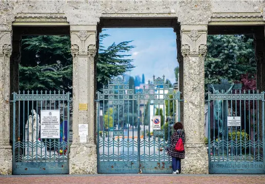  ??  ?? Il cimitero chiuso, una preghiera in silenzio, sulla soglia. Anche ieri il bollettino regionale, nel tardo pomeriggio, ha annunciato dati choccanti