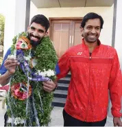  ?? — R. PAVAN KUMAR ?? Srikanth Kidambi (left) is all smiles as he shows off his World Championsh­ip silver medal alongside coach Pullela Gopichand at the Pullela Gopichand Badminton Academy in Hyderabad on Tuesday.