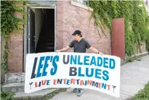  ?? ASHLEE REZIN GARCIA/ SUN-TIMES ?? Warren Berger, owner of Lee’s Unleaded Blues in the Grand Crossing neighborho­od, shows off an original, hand-painted tin sign from the 1960s.