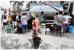  ??  ?? Severe inconvenie­nce: A woman carrying buckets of water from a water truck at her village in Quezon city. — AP