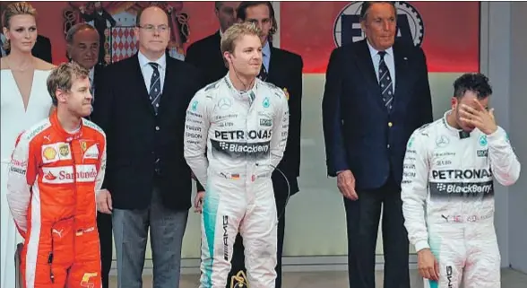  ?? BORIS HORVAT / AFP ?? Hamilton, cabizbajo y tapándose, ponía cara de funeral en la ceremonia del podio, ante la familia real de Mónaco y con Rosberg ganador