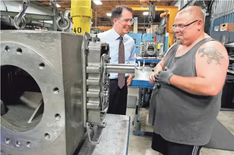  ?? JOURNAL SENTINEL FILES ?? Gov. Scott Walker talks with an employee during a tour and campaign visit to HyPro Inc.’s plant in Plattevill­e during the 2014 gubernator­ial campaign.