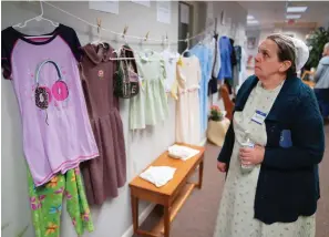  ?? The Associated Press ?? ■ Darlene Shirk looks at the clothes of sexual assault survivors from Amish, Mennonite and other plain-dressing religious groups on display at a child abuse prevention seminar on April 29 in Leola, Pa.