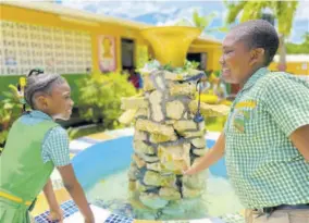  ?? ?? Pell River students Dejanae Pearce (left) and Jaheim Jerry enjoying the new fountain in the school’s renovated peace garden.