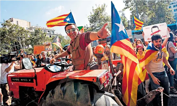  ??  ?? A farmer is cheered by students as he drives his tractor near the University of Barcelona during a pro-referendum protest called by the farmers’ union