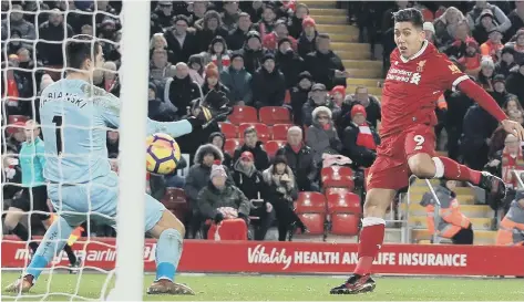  ??  ?? Roberto Firmino finishes off to put Liverpool two up against Swansea in last night’s 5-0 mauling at Anfield.