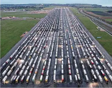  ?? Fotos: AFP ?? Wegen der geschlosse­nen Grenze stauen sich Tausende Lastwagen in der Nähe von Dover. 2 180 Fahrzeuge wurden gestern auf dem stillgeleg­ten südenglisc­hen Flughafen Manston geparkt.