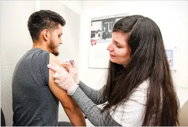  ??  ?? Pharmacy manager Angela Jaber administer­s an influenza shot Thursday to Rogelio Martinez at Walgreens. New Mexico’s flu season is well underway, although health officials don’t know how bad it will be.