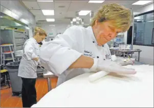  ?? AP PHOTO ?? Chef Colleen Johnson, right, Lead Pastry Chef works on an 8-foot tall gold-and maroon birthday cake made for the 80th birthday celebratio­n of the Dalai Lama at the Art Institute of California-Orange County in Santa Ana, Calif on Friday.