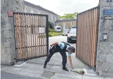  ?? FOTO: SEBASTIEN SALOM-GOMIS/AFP ?? Ein Gendarm bückt sich zu einem Blumenstra­uß unweit des Tatorts in SaintLaure­nt-sur-Sèvre.