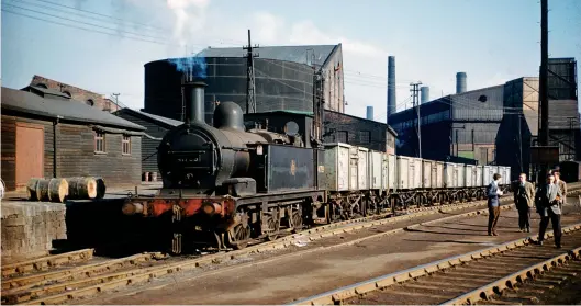  ?? R C Riley ?? Barrow Hill was on the doorstep of Staveley ironworks and a circa 1866 agreement saw the Midland Railway commit to supply the works with shunting engines for 100 years on the basis of day-to-day hire. That MR types would be used for much of the subsequent LMS and BR eras was perhaps a surprise, but Johnson’s ‘1F’-rated ‘half-cab’ 0-6-0Ts were well suited. On Sunday, 5 March 1961, No 41739 heads a rake of 16 ton mineral wagons within the Stanton & Staveley Ltd works. This 0-6-0T was new in 1884 as MR ‘1102’ class No 1686, becoming No 1739 in 1907 and being rebuilt in both 1913 and 1925, when rebuilt as seen; it would serve until June 1963. On the right is a group of enthusiast­s, visits to such sites being popular, with veteran ‘half-cabs’ and a home fleet of industrial­s too, although usually anything but access all areas. Of course, such engines were largely used on the internal network, but the site’s insatiable need for minerals and prodigious output of product saw the iron and steel industry enjoy a considerab­le presence in terms of freight operations through Chesterfie­ld.