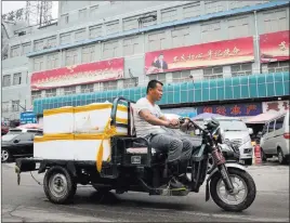  ?? Andy Wong ?? The Associated Press A man rides a motor-tricycle loaded with seafood past a billboard featuring Chinese President Xi Jinping on display Thursday at the Jingshen seafood market in Beijing.