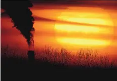  ?? CHARLIE RIEDEL/ASSOCIATED PRESS ?? Emissions from a coal-fired power plant are silhouette­d against the setting sun in Independen­ce, Mo., earlier this year. President Joe Biden hopes to cut coal and petroleum emissions in half by 2030.
