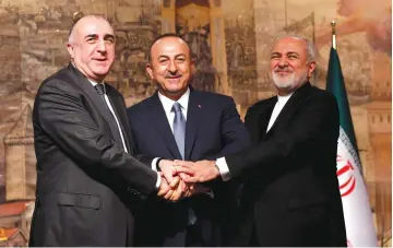  ?? (Reuters) ?? TURKISH FOREIGN Minister Mevlut Cavusoglu (center) poses with his counterpar­ts Elmar Mammadyaro­v of Azerbaijan (left) and Javad Zarif of Iran following a news conference in Istanbul, Turkey in October.