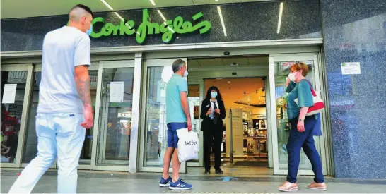  ?? CRISTINA BEJARANO ?? Un empleado de El Corte Inglés con gel hidroalcoh­ólico para los clientes espera en la puerta de entrada de uno de los grandes almacenes del grupo la llegada de algún cliente