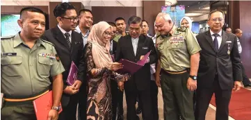  ??  ?? Mohamad Sabu (front third right) and Defence Forces chief Tan Sri Zulkifli Zainal Abidin (second right) take a closer look at a recipient’s award. At right is secretary of the Ministry of Defence Datuk Halimi Abd Manaf. — Bernama photo