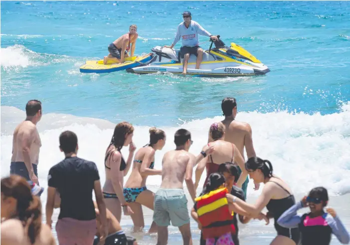  ?? Picture: GLENN HAMPSON ?? Lifeguards at Surfers Paradise beach keep an eye on beachgoers both inside and outside of the flags on one of the busiest days of the year yesterday.