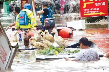  ??  ?? Rescue workers helping people on a flooded street in Loudi, Hunan province. — AFP photo