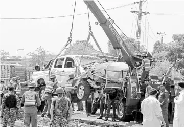  ??  ?? Pakistani officials use a crane to lift a security vehicle at the site of suicide bomb attack in Peshawar. — AFP photo