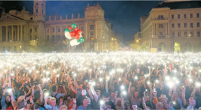  ??  ?? Handyleuch­ten gegen die autokratis­che Finsternis: Zehntausen­de Anti-Orbán-Demonstran­ten setzten Samstagabe­nd in Budapest auch auf allerhand Symbolik.