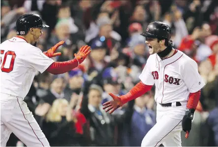  ?? MADDIE MEYER/GETTY IMAGES ?? Mookie Betts and Andrew Benintendi celebrate after each scored a run on a hit by teammate J.D. Martinez during the decisive fifth inning as the Boston Red Sox topped the Los Angeles Dodgers 4-2 in Game 2 of the World Series at Fenway Park in Boston on Wednesday.