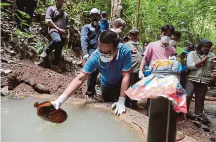  ?? [FOTO FATHIL ASRI /BH] ?? Petugas Kementeria­n Kesihatan mengambil sampel air tadahan bukit di Sungai Pertang di Kampung Kuala Koh, semalam.