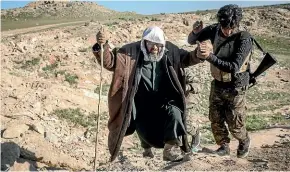  ?? GETTY IMAGES ?? A Syrian Democratic Forces fighter helps a man arriving at an SDF position after he walked for hours to flee the fighting around Bagouz, the last village held by Islamic State.