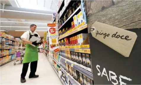  ??  ?? Portugal on July 6. — Reuters photo A worker arranges products on the display shelves at a Pingo Doce supermarke­t in Lisbon, STOCKING SUPERMART: