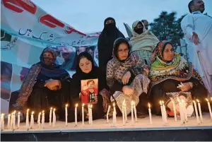  ?? ?? People light candles in Peshawar on Wednesday to pay tribute to the victims of the suicide blast. — afp