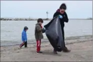  ?? BRIANA CONTRERAS — THE MORNING JOURNAL ?? Melissa Counts from Elyria is helped by her sons, from left, Liam, 4, and Caleb, 6, to pick up trash on the beach of Lakeview Park, 1800 W Erie Ave. in Lorain, during the park’s annual Earth Day Park & Beach Clean Up on April 21.