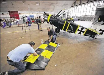  ?? TY GREENLEES PHOTOS / STAFF ?? Todd Palmer (left) and pilot/owner John Crisp (right) prepare to attach a wing to Crisp’s 3/4 scale Fokker Dr-1 triplane at the National Museum of the U.S. Air Force on Friday. This airplane is one of many participat­ing in the WWI Dawn Patrol...