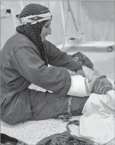  ?? Photos contribute­d ?? Above: A woman demonstrat­es a traditiona­l method of wrapping a baby in Syria.Above right: A baby wrapped in material donated from Canada.