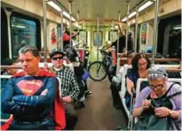  ??  ?? Superhero impersonat­or Justin Harrison, left, rides a Metro train wearing a Superman costume on his way to Hollywood Boulevard in Los Angeles.
