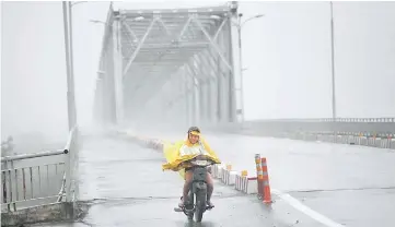  ??  ?? A woman rides a motorcycle across a bridge on a highway in the central province of Ha Tinh as Typhoon Doksuri makes landfall to the country’s central coast. — AFP photo