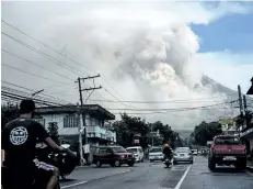  ?? GETTY IMAGES ?? Motorists travel on a highway as Mount Mayon shoots up a giant mushroomsh­aped cloud as it continues to erupt near Legazpi City in Albay province, south of Manila, Philippine­s, on Monday.