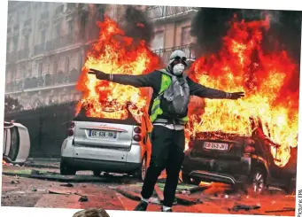  ??  ?? Inferno: A rioter in Paris on Saturday