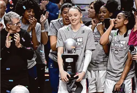  ?? Jessica Hill/Associated Press ?? UConn guard Paige Bueckers, center, holds the tournament’s most outstandin­g player trophy after defeating Georgetown in the Big East Conference tournament at Mohegan Sun Arena.