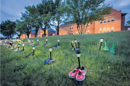  ?? DENNIS OWEN • REUTERS ?? Pairs of children’s shoes and toys are seen at memorial in front of the former Kamloops Indian Residentia­l School on Monday after the remains of 215 children, some as young as three years old, were found at the site last week.