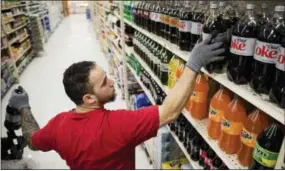  ?? MATT ROURKE — THE ASSOCIATED PRESS ?? In this photo, Albert Delarosa stocks shelves with Coca-Cola products at the IGA supermarke­t in the Port Richmond neighborho­od of Philadelph­ia. Less than three months into Philadelph­ia’s new tax on sweetened drinks, the stakes have escalated: Beverage...