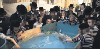  ?? ODED BALILTY — THE ASSOCIATED PRESS, FILE ?? Ultra-Orthodox Jews surround a plastic pool with water and fish as they participat­e in a Tashlich ceremony in the town of Bnei Brak near Tel Aviv, Israel, in 2012. Tashlich, which means “to cast away” in Hebrew, is the practice by which Jews go to a large flowing body ofwater and symbolical­ly throw away their sins by throwing a piece of bread, or similar food, into thewater before the Jewish holiday of Yom Kippur, which start today.