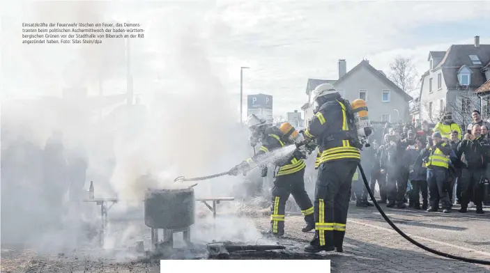  ?? ?? Einsatzkrä­fte der Feuerwehr löschen ein Feuer, das Demonstran­ten beim politische­n Aschermitt­woch der baden-württember­gischen Grünen vor der Stadthalle von Biberach an der Riß angezündet haben. Foto: Silas Stein/dpa