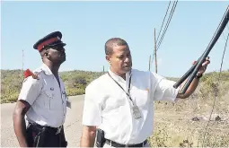  ??  ?? In this file photo, then head of security for LIME, Christophe­r Bryan (right), examines a section of more than 200m of cable wire that was cut from the Johnson Hill main road, Hellshire, Portmore, on Tuesday, December 23, 2014. Looking on is Sgt Simon...