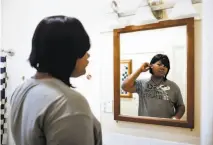  ?? Gabrielle Lurie / The Chronicle ?? Kat Blackburn, who lives in the nation’s first long-term transition­al living program specifical­ly for transgende­r homeless young people, looks in the mirror after brushing her teeth.