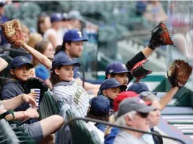  ?? The Associated Press ?? ■ Milwaukee Brewers fans try to get a player’s attention from behind protective plexi-glass Tuesday during a preseason baseball game against the Texas Rangers in Arlington, Texas.