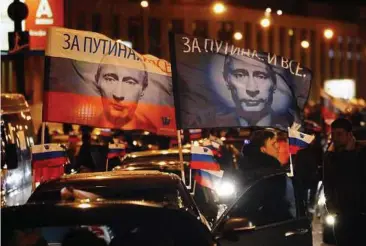  ?? — EPA ?? Support on wheels: Russians driving cars decorated with flags and portraits of Putin during the convoy in Moscow.